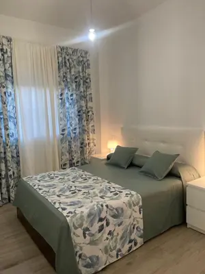 a bedroom with a bed with blue and white curtains at La casa de Cris in Sanlúcar de Barrameda