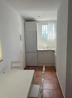 a kitchen with a table and a white refrigerator at Villa con piscina in Chiclana de la Frontera