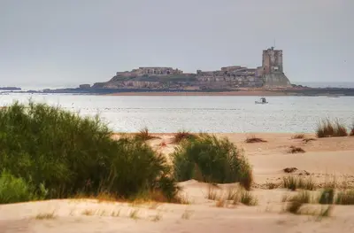 a view of a beach with a castle in the water at Casa Chiclana Centro in Chiclana de la Frontera
