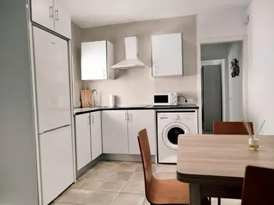 a kitchen with white cabinets and a table and a washing machine at Casa Chiclana Centro in Chiclana de la Frontera