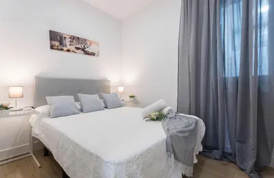 a white bedroom with a bed with white sheets and a window at Plaza Caballo 3 Dormitorios Vistas in Jerez de la Frontera