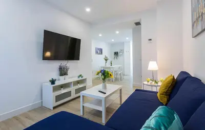 a living room with a blue couch and a tv at Plaza Caballo 3 Dormitorios Vistas in Jerez de la Frontera