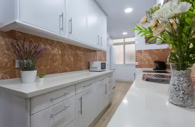 a kitchen with white cabinets and a vase of flowers at Plaza Caballo 3 Dormitorios Vistas in Jerez de la Frontera