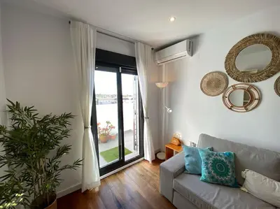 a living room with a couch and a large window at Apartamento Mati, Terraza 55 m2 in Sanlúcar de Barrameda