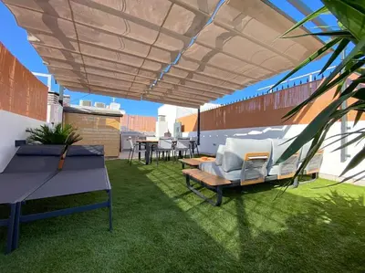 a patio with chairs and tables on a roof at Apartamento Mati, Terraza 55 m2 in Sanlúcar de Barrameda