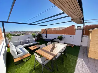 a patio with a table and chairs on a roof at Apartamento Mati, Terraza 55 m2 in Sanlúcar de Barrameda