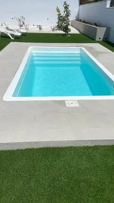 a large blue swimming pool next to a lawn at Casa Lili in Conil de la Frontera