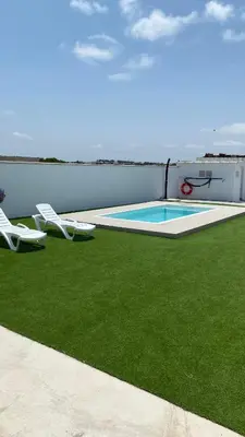 a patio with two lawn chairs and a swimming pool at Casa Lili in Conil de la Frontera