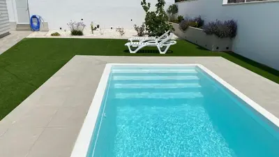 a swimming pool with a bench next to a house at Casa Lili in Conil de la Frontera