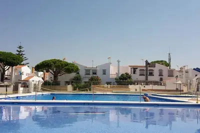 a large swimming pool with people in the water at Estupendo adosado en La Barrosa, a 700 m de la Playa in Chiclana de la Frontera