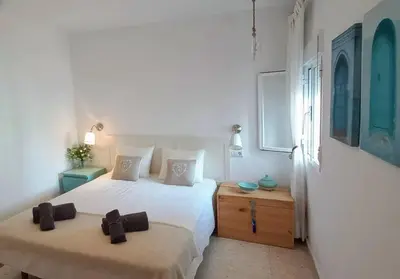 a white bedroom with two beds and a window at Estupendo adosado en La Barrosa, a 700 m de la Playa in Chiclana de la Frontera
