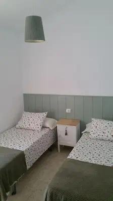 a room with two beds and a table and a lamp at Estupendo adosado en La Barrosa, a 700 m de la Playa in Chiclana de la Frontera