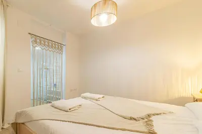 a white bedroom with a bed and a window at Allo Apartments Morenos II 1ºC Centro 2 Habitaciones in Jerez de la Frontera