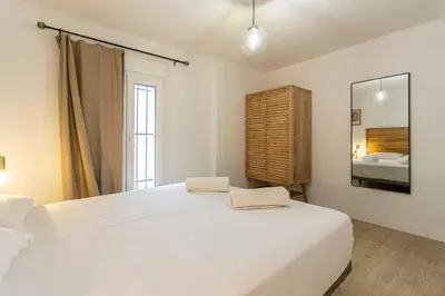 a bedroom with a large white bed and a mirror at Allo Apartments Morenos III Bajo A Centro 2 Habitaciones in Jerez de la Frontera