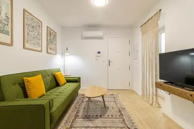 a living room with a green couch and a tv at Allo Apartments Morenos III Bajo A Centro 2 Habitaciones in Jerez de la Frontera