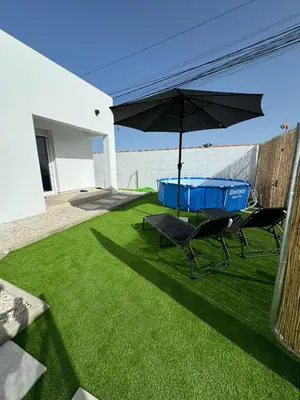 a patio with two chairs and an umbrella on the grass at Apartamento El Oasis in Chiclana de la Frontera