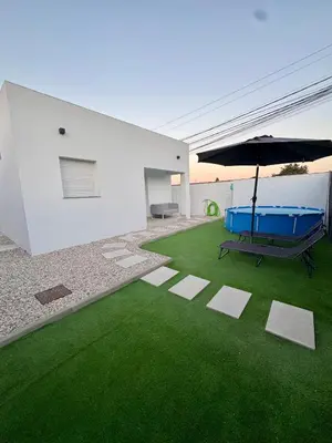 a house with a green yard with a bench and an umbrella at Apartamento El Oasis in Chiclana de la Frontera