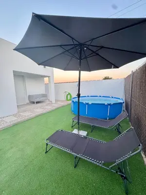 an umbrella and a chair with a tub in a yard at Apartamento El Oasis in Chiclana de la Frontera