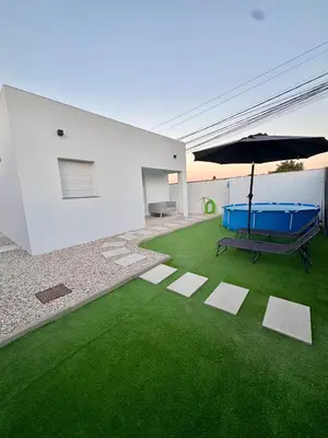 a house with a green yard with a bench and an umbrella at Apartamento El Oasis in Chiclana de la Frontera
