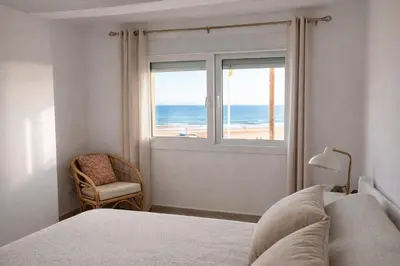 a bedroom with a bed and a view of the beach at Mirando al Mar con Wifi y Terraza 1ª línea playa in Cádiz
