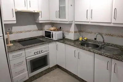 a kitchen with white cabinets and a sink and a microwave at Mirando al Mar con Wifi y Terraza 1ª línea playa in Cádiz