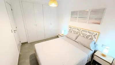 a small bedroom with a white bed and white cabinets at Rincón del Atlántico in Rota