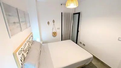 a small white bedroom with a bed in it at Rincón del Atlántico in Rota
