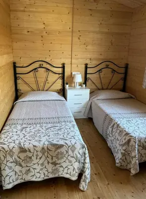 two beds in a room with wooden walls at Bungalow Sol in Chiclana de la Frontera