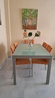 a glass table with a vase with flowers in it at Apartamento céntrico con garaje opcional in Sanlúcar de Barrameda