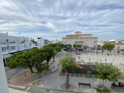 a park with trees and benches in a city at Apartamento Malandar in Sanlúcar de Barrameda