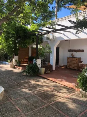 a patio of a white house with a tree at Abajo Stijlvol appartement met zwembad en tuin in Cádiz