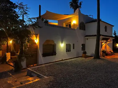 a white house at night with lights at Abajo Stijlvol appartement met zwembad en tuin in Cádiz