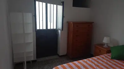 a bedroom with a door and a bed and a dresser at Casa del Prendi in Jerez de la Frontera