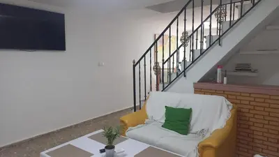a living room with a yellow chair with a green pillow at Casa del Prendi in Jerez de la Frontera