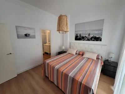 a bedroom with a bed with a striped blanket at Casa Teresa in Sanlúcar de Barrameda