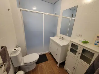 a white bathroom with a toilet and a sink at Casa Teresa in Sanlúcar de Barrameda