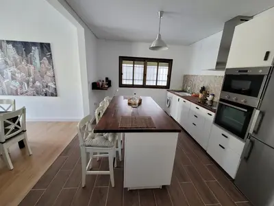 a kitchen with white cabinets and a wooden counter top at Casa Teresa in Sanlúcar de Barrameda