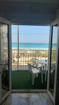 a balcony with a table and chairs and the beach at La Casa Azul in Chiclana de la Frontera