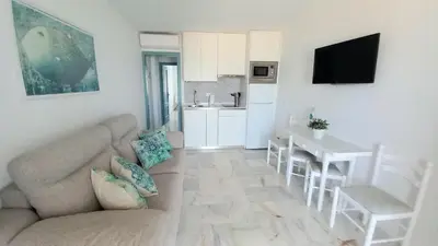 a living room with a couch and a table and a kitchen at La Casa Azul in Chiclana de la Frontera