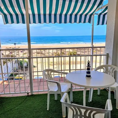 a table and chairs on a balcony with the beach at La Casa Azul in Chiclana de la Frontera