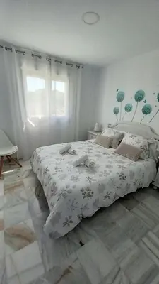a bedroom with a large bed with a white comforter at La Casa Azul in Chiclana de la Frontera