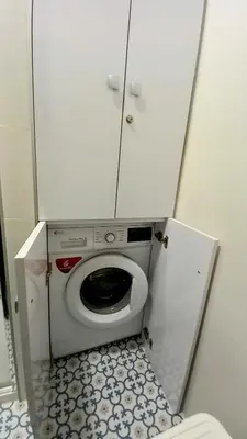 a small bathroom with a washing machine in a cabinet at La Casa Azul in Chiclana de la Frontera
