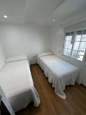 two beds in a room with white walls and wooden floors at Vino Amontillado 5 in El Puerto de Santa María