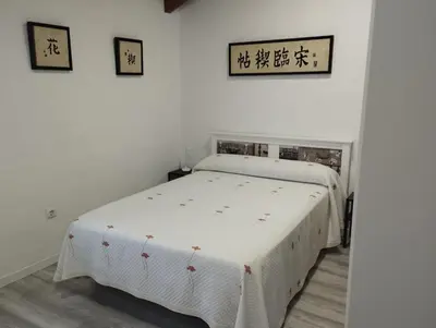 a bedroom with a white bed in a room at Casa Yuxiao rincón de tranquilidad in Cádiz