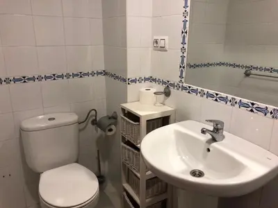 a white bathroom with a toilet and a sink at Apartamento Playa La Muralla in El Puerto de Santa María