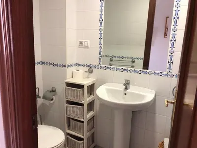 a bathroom with a sink and a toilet and a mirror at Apartamento Playa La Muralla in El Puerto de Santa María