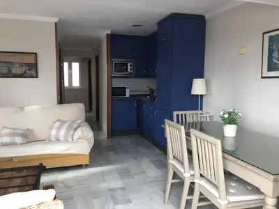 a living room with blue cabinets and a table and a couch at Apartamento Playa La Muralla in El Puerto de Santa María