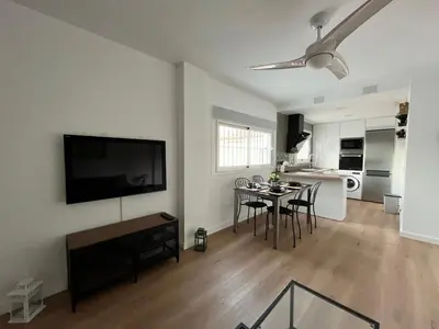 a living room with a table and a tv on a wall at Apartamento Pleamar in Sanlúcar de Barrameda