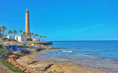 a lighthouse on the shore of a beach at YourHouse Apartamentos Andasol BA in Chipiona