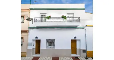 a white building with a balcony with two plants on it at YourHouse Apartamentos Andasol BA in Chipiona